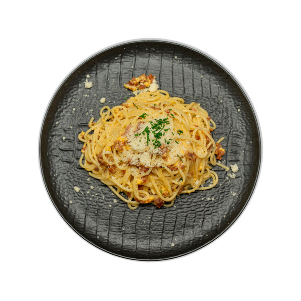 Espaguetis a la carbonara con taquitos de jamón, salsa con yemas de huevo, pimienta y Grana Padano